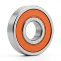 Edge Bearing with orange seals and a silver steel ring, standing upright on its edge against a white background