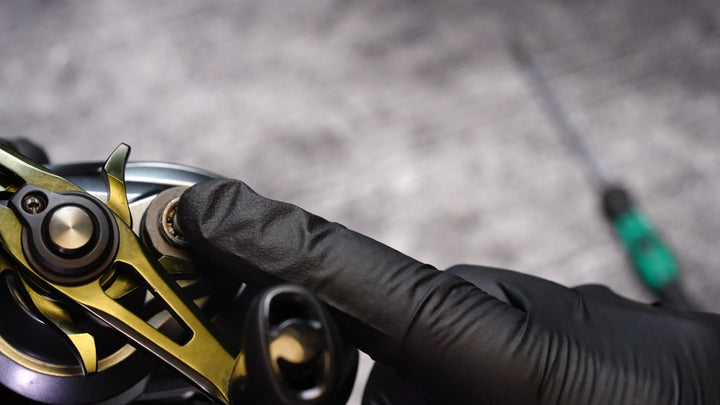 A gloved fingertip presses the new spool bearing into its seat