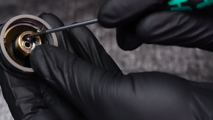 A pick lifts the wire clip out of the side plate