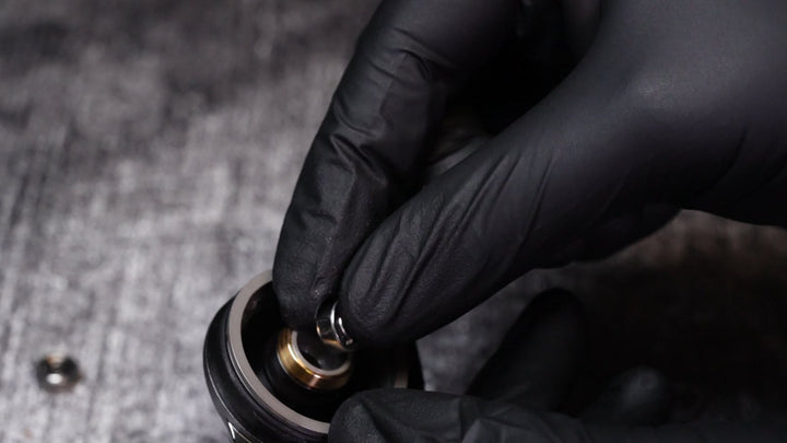 Gloved fingers set a new spool bearing into the side plate